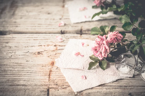 Rosa Rosen mit Gläsern auf Holztisch — Stockfoto