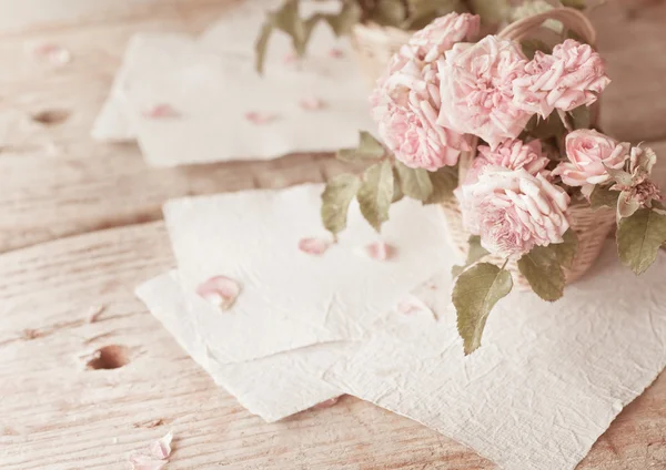 Rosas rosadas con papeles sobre mesa de madera — Foto de Stock