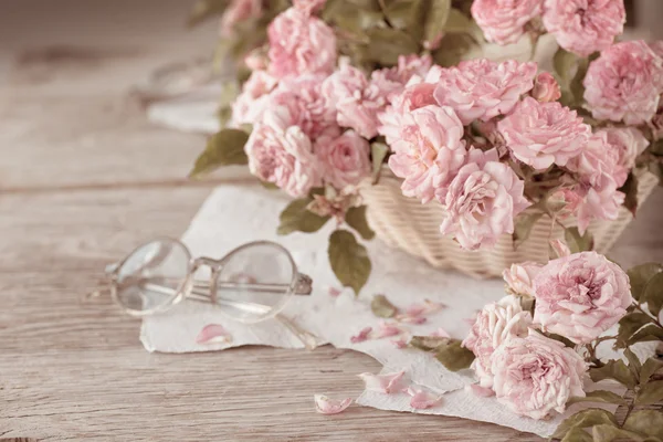 Розовые розы со стеклами на деревянном столе — стоковое фото