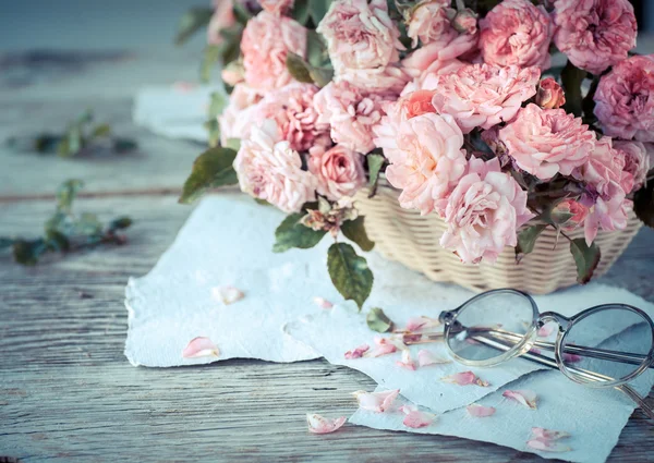 Рожеві троянди в окулярах на дерев'яному столі — стокове фото