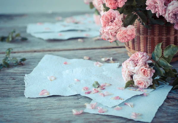 Rosas rosadas con papeles sobre mesa de madera — Foto de Stock