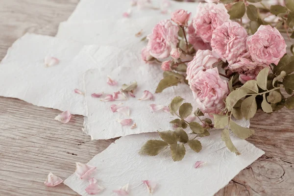 Rosas rosadas con papeles sobre mesa de madera — Foto de Stock