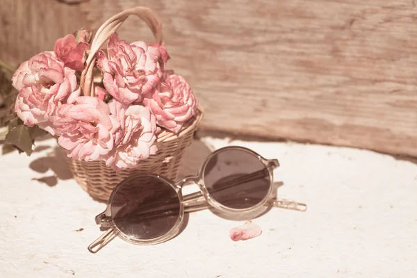 Roze rozen met bril op houten tafel — Stockfoto