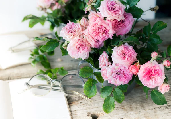 Rosas sobre mesa con vasos y papel . — Foto de Stock