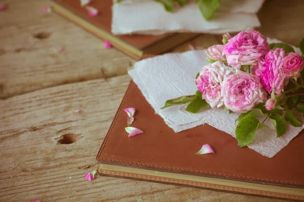 Rosas cor de rosa com papéis na mesa de madeira — Fotografia de Stock