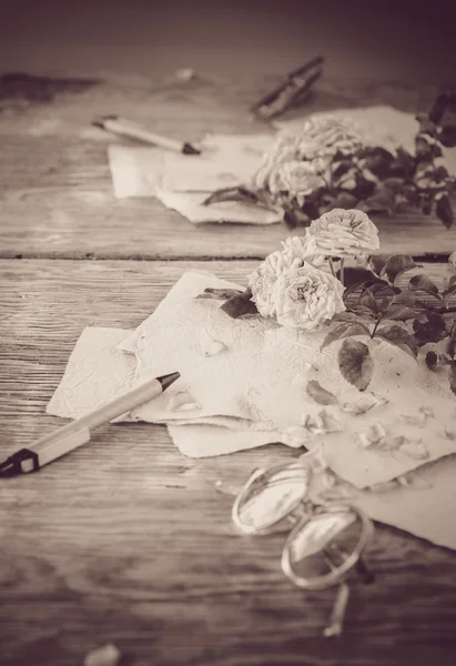 Розы со стеклами на деревянном столе — стоковое фото