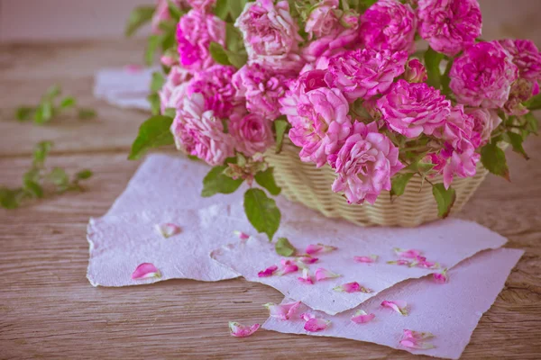 लकड़ी की मेज पर कागज के साथ गुलाबी गुलाब — स्टॉक फ़ोटो, इमेज