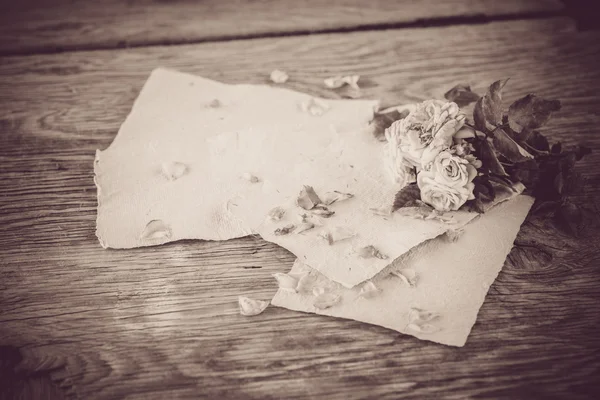 Roses with papers on wooden table — Stock Photo, Image