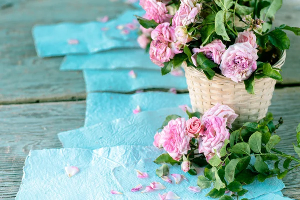 Rosas cor de rosa com papéis na mesa de madeira — Fotografia de Stock