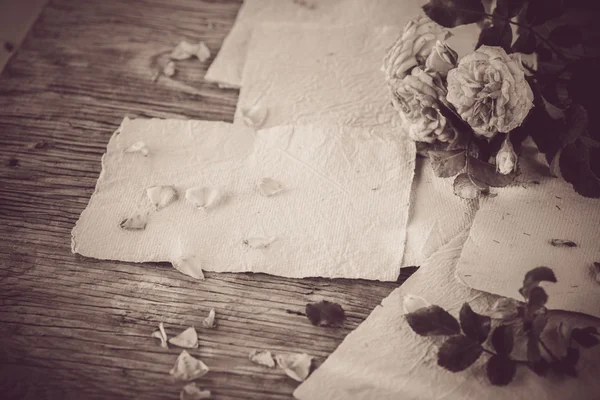 Roses with papers on wooden table — Stock Photo, Image