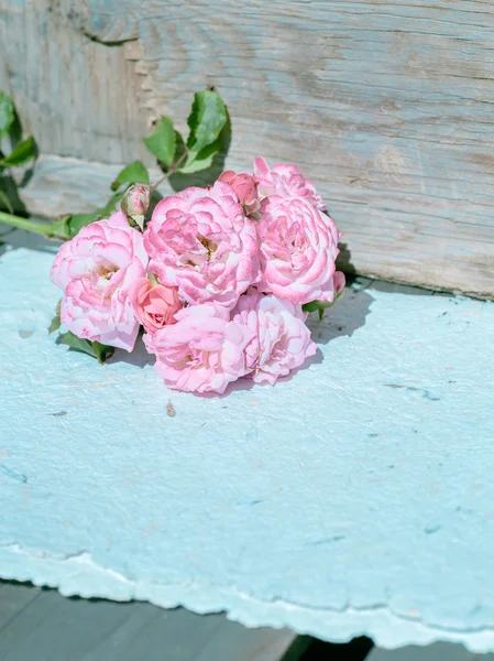 Розовые розы с бумагами на деревянном столе — стоковое фото