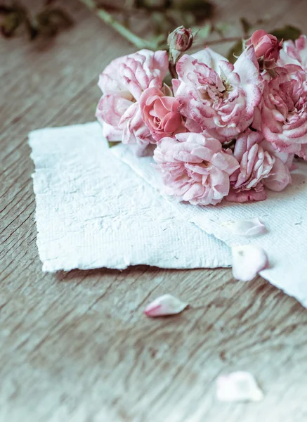 木製のテーブルに紙とピンクのバラ — ストック写真