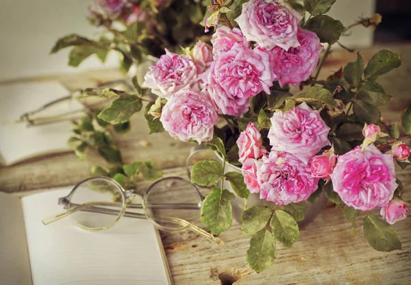 Rosa Rosen mit Gläsern auf Holztisch — Stockfoto