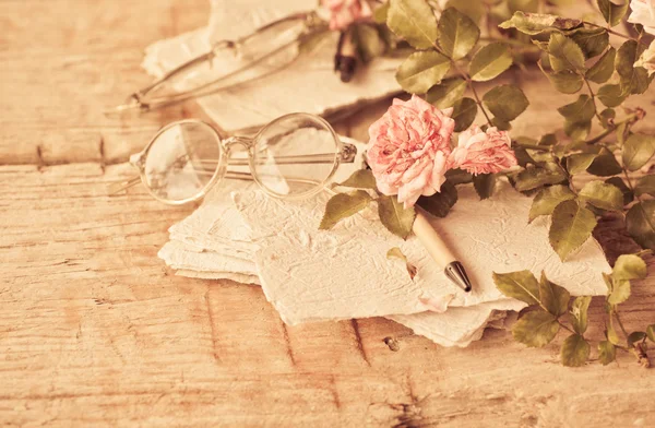 Rosas cor de rosa com óculos na mesa de madeira — Fotografia de Stock