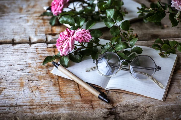 Rosa Rosen mit Gläsern auf Holztisch — Stockfoto