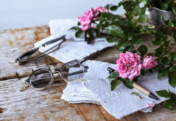 Rosas rosadas con gafas sobre mesa de madera — Foto de Stock