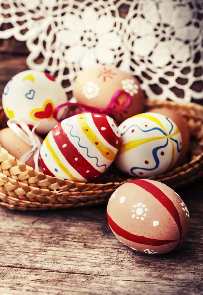 Coloridos huevos de Pascua en una pequeña cesta . — Foto de Stock