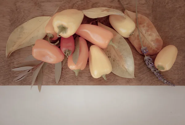 Pimientos sobre tabla de madera, hojas de otoño — Foto de Stock