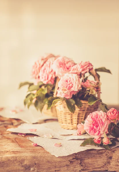 Pink roses with papers on wooden table — Stock Photo, Image