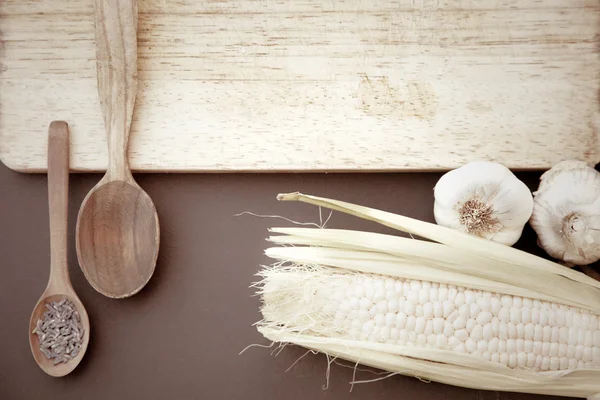 Close-up of garlic, spoons and board — Stock Photo, Image