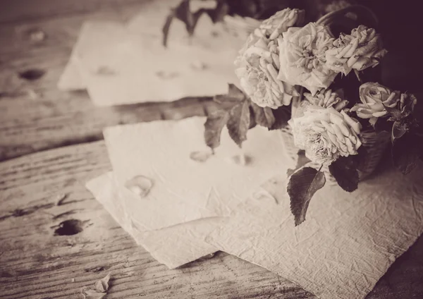 Rosas con papeles sobre mesa de madera — Foto de Stock