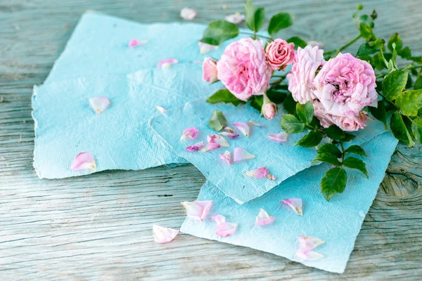 Rosas cor de rosa com papéis na mesa de madeira — Fotografia de Stock