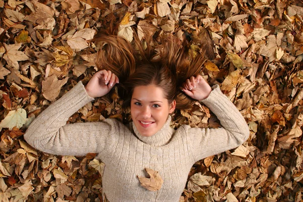Bella ragazza coperta di foglie autunnali — Foto Stock