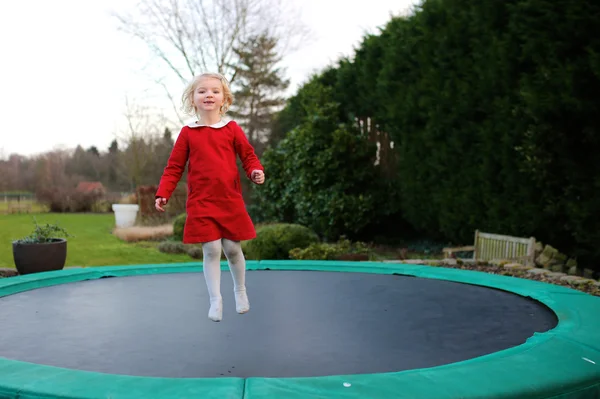 Happy little girl jumping on trampoline — Stock Photo, Image