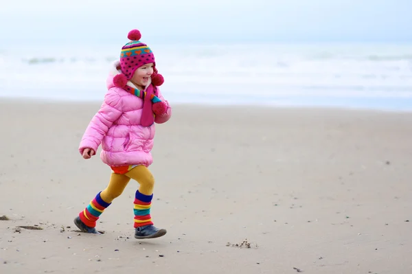 Милая маленькая девочка бегает по зимнему пляжу — стоковое фото