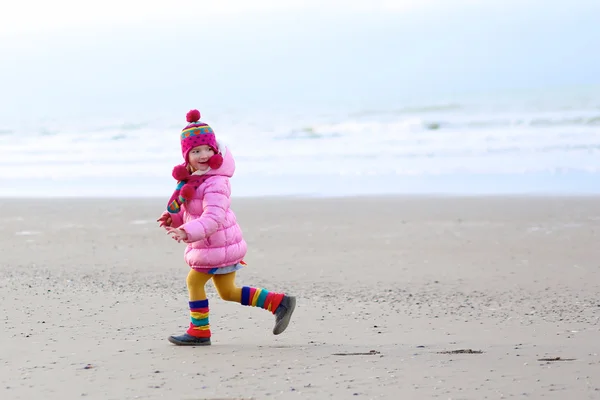 Nettes kleines Mädchen läuft am Winterstrand — Stockfoto