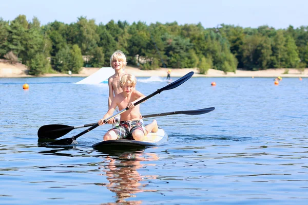 Tonårspojke camping och njuter av stand up paddle på sjön — Stockfoto