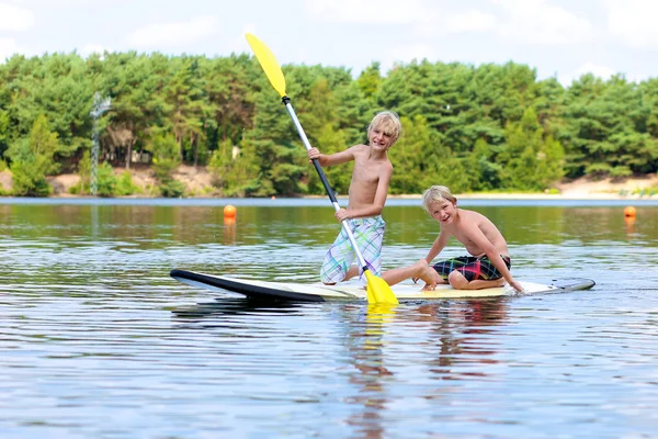 Två pojkar njuter stå upp paddla på sjön — Stockfoto