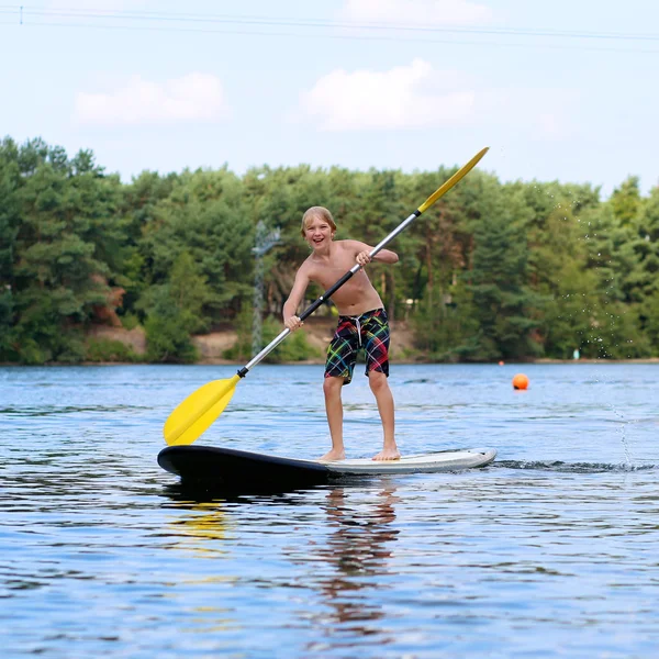 Tonårspojke camping och njuter av stand up paddle på sjön — Stockfoto