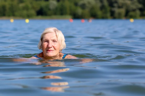 Starší žena, plavání v jezeře — Stock fotografie