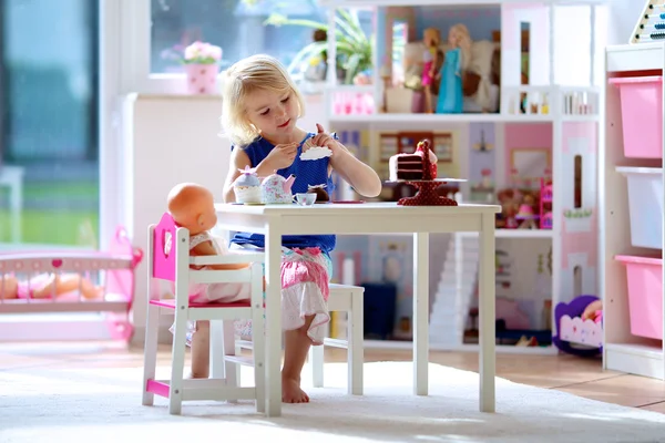 Маленькая девочка играет в чаепитие с куклами — стоковое фото