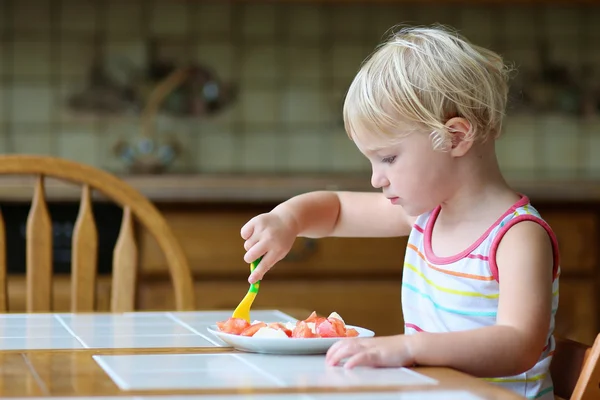 Здоровая маленькая девочка ест салат на кухне — стоковое фото
