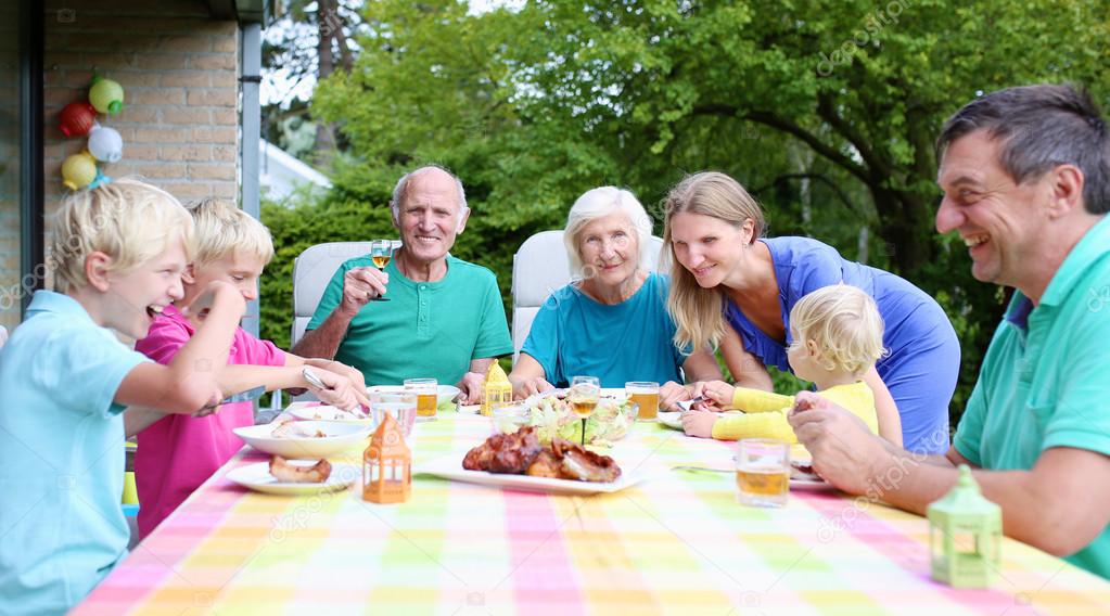 Big family of seven having meal outdoors