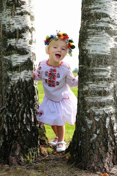 Lille ukrainsk pige i traditionel kjole spiller på markerne - Stock-foto