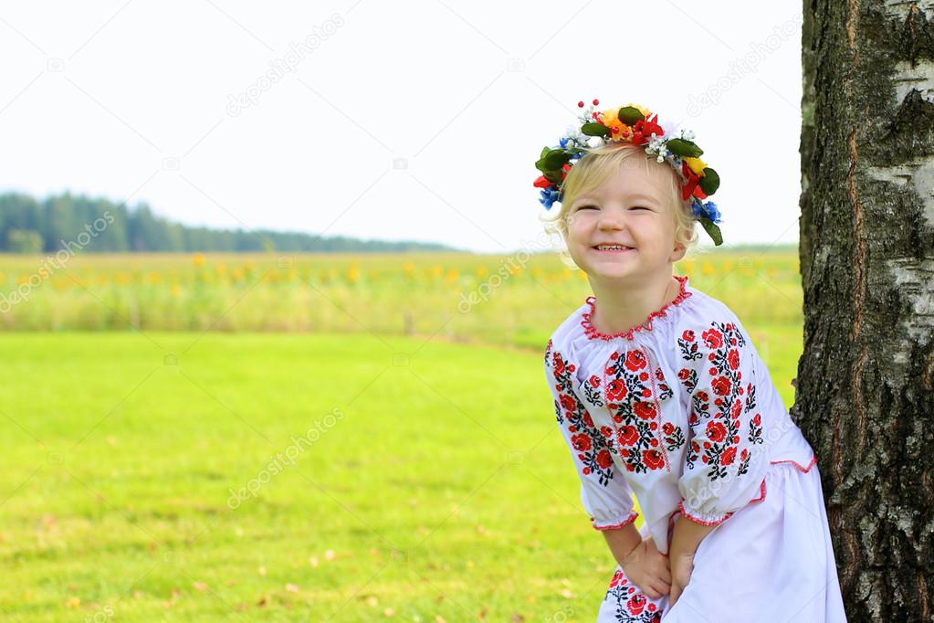 Little Ukrainian girl in traditional dress playing in the fields