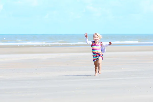 Kleines glückliches Mädchen spielt am Strand — Stockfoto
