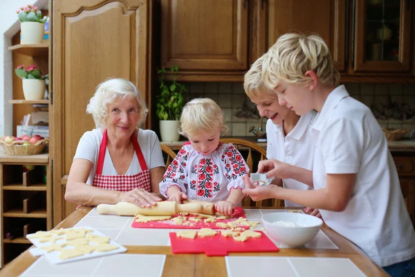 Бабушка с внуками готовит на кухне — стоковое фото