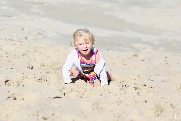 Маленькая счастливая девочка играет на пляже — стоковое фото