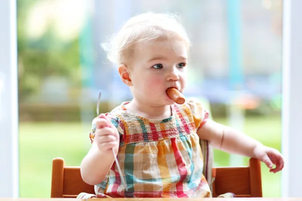 Engraçado menina comendo salsicha de garfo — Fotografia de Stock