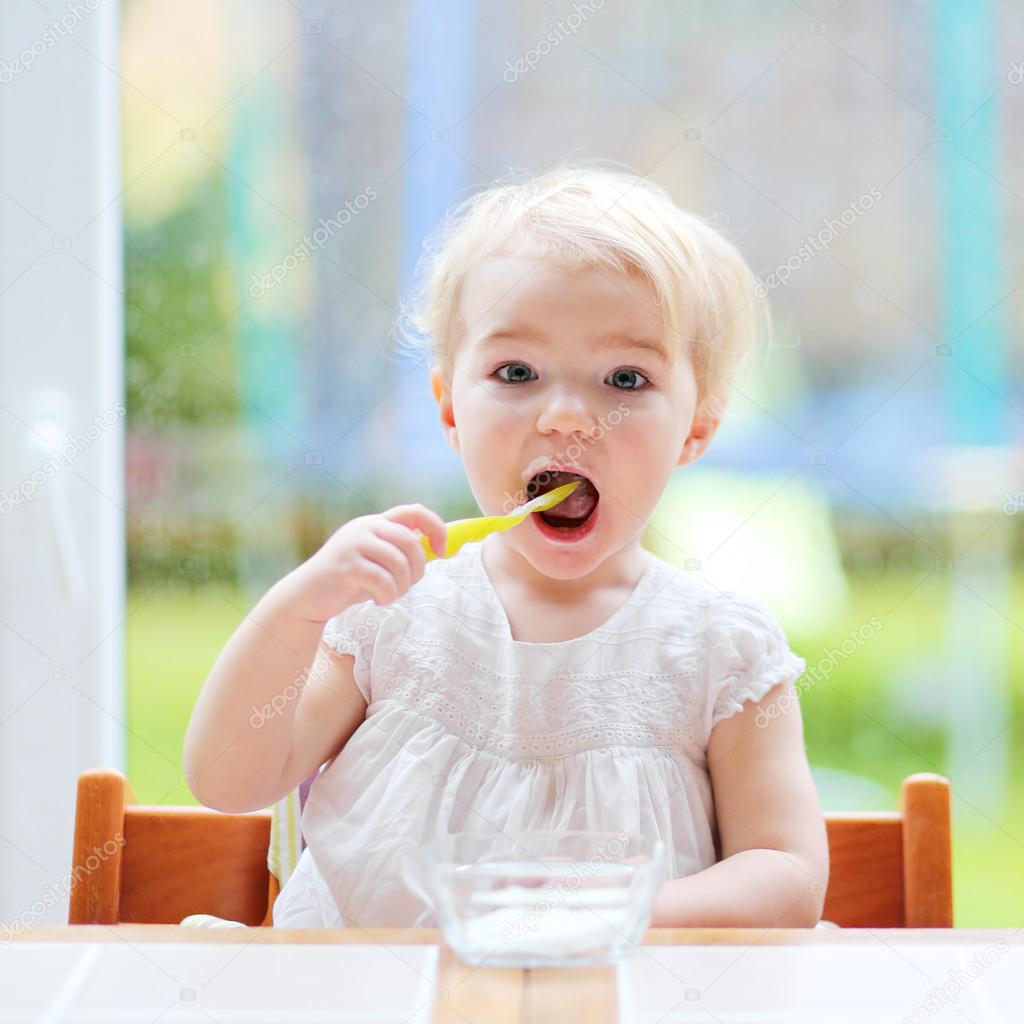 Toddler girl eating yogurt from spoon