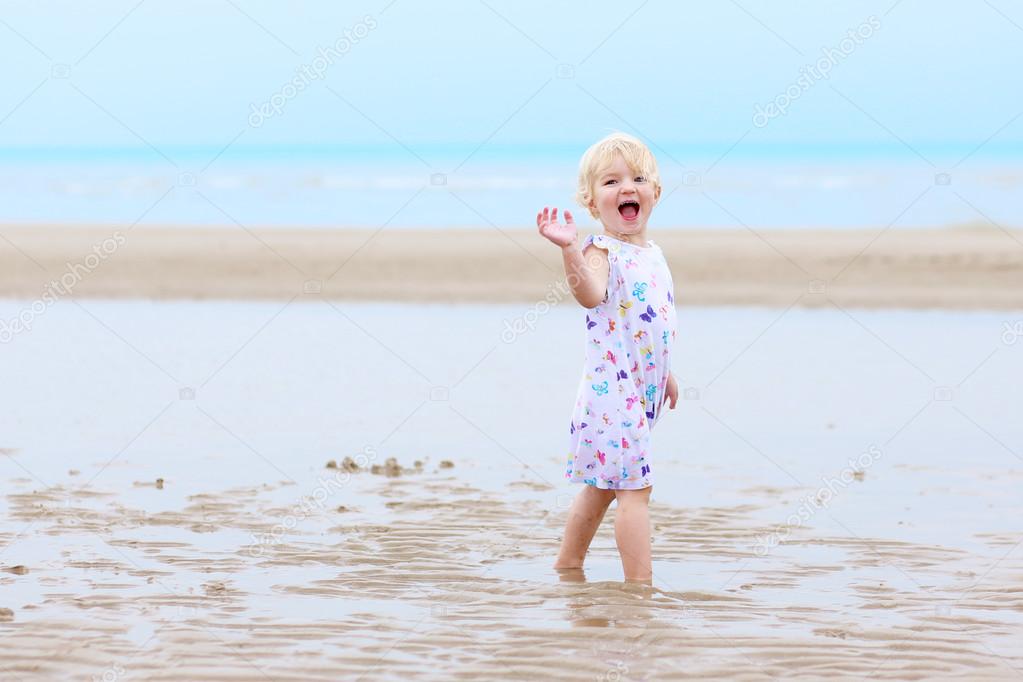 Happy toddler girl playing on the beach