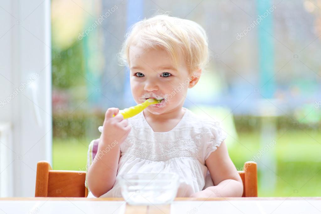 Toddler girl eating yogurt from spoon