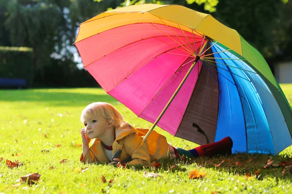 Kleines Mädchen läuft mit buntem Regenschirm — Stockfoto