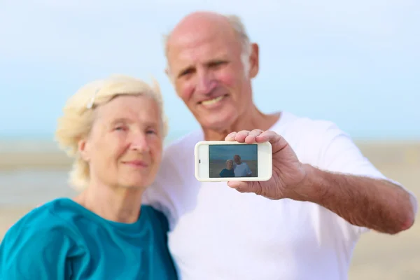 Äldre par tar själv mobila foto på stranden — Stockfoto