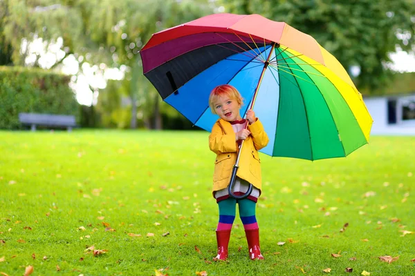 Kleines Mädchen läuft mit buntem Regenschirm — Stockfoto