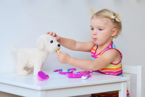 Adorable girl playing with toy dog — Stock Photo, Image